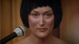 Meryl Streep, with short black hair, sits in court in the movie A Cry in the Dark