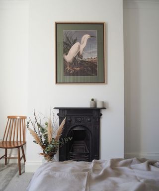 white bedroom with black fireplace and artwork on wall