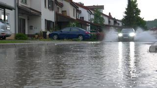 Flooded residential road with car splashing through the water