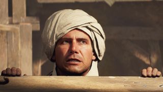 Indiana Jones grimacing and wearing a turban as he lifts himself up over a ledge.