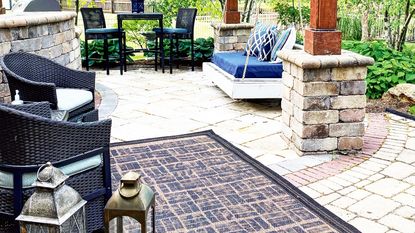 a painted outdoor rug in a patio area with patio seating and a double outdoor swing
