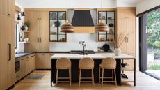 kitchen with pale wood cabinets and dark island with white countertop