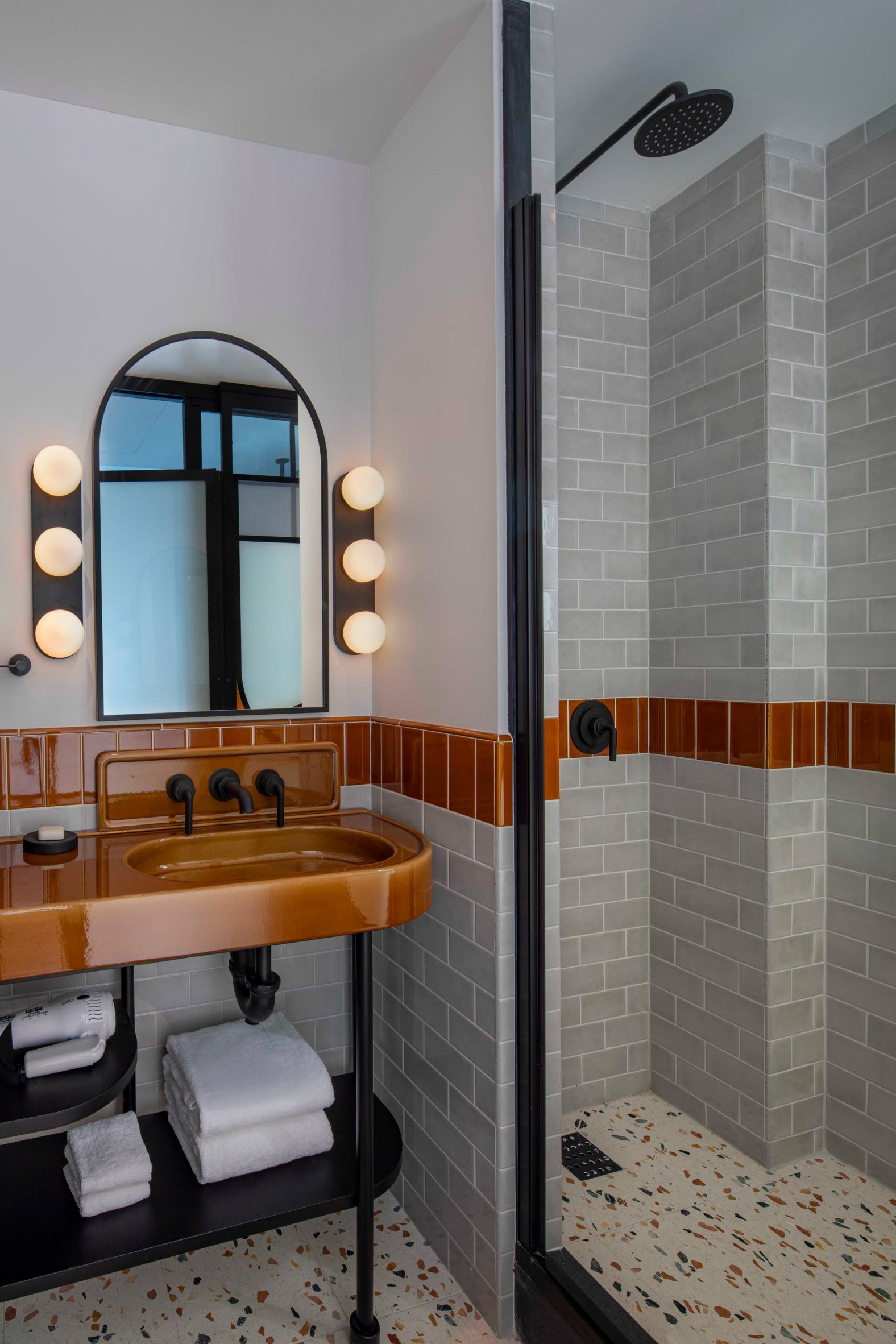 A layeredly decorated hotel features extravagant decor in its communal areas, including sumptuous chandelier, paper lanterns, lush plants, and patterned upholstery, with quirky, contemporary rooms characterized by color-block interiors and textural surfaces.