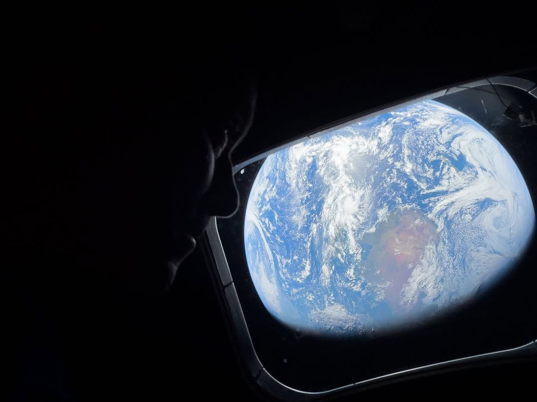 A man looks out the window at Earth from his space capsule.