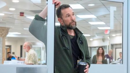 Dr. Robby leans on a door frame