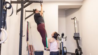 Woman performs a pull-up using assistance from a resistance band