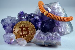 A fake bitcoin laid on some amethyst crystals