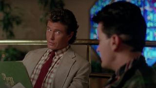 Tom Berenger looks over at Charlie Sheen while holding a menu in Major League.