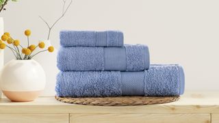 A pile of three blue towels on a wooden countertop