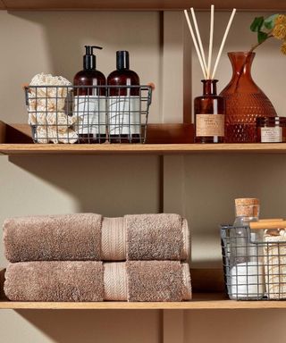 Mink towels on wood bathroom shelf with toiletries
