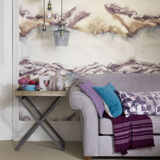 A light purple sofa in front of dramatic patterned wallpaper