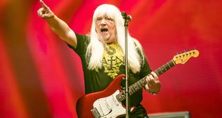 Andy Scott of the Sweet points to the crowd has he plays a red Strat