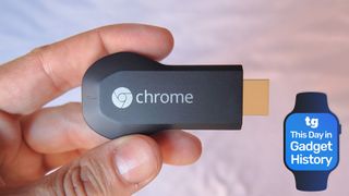 A hand holding the first-generation Chromecast