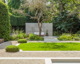 gravel and limestone patio area with yew domes and seating area in modern garden