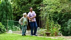 An older woman and a younger man, who is her caregiver, walk and laugh together outside.