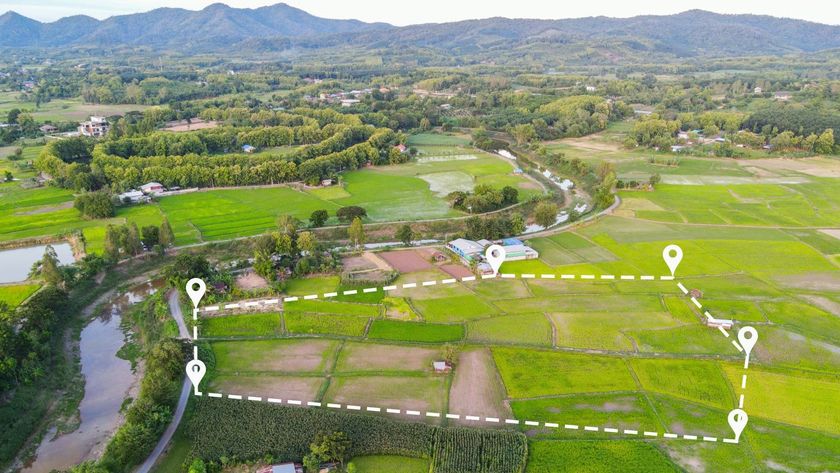 A landscape view of a green field with a boundary line marked out in white dotted lines