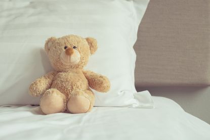 A teddy bear on a bed.