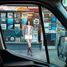 Model wearin a zebra print jacket and beige dress with brown moto boots sold at Nasty Gal shot from the inside of a van