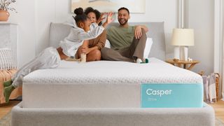 A family sit on the new Casper Snow Hybrid mattress in a bedroom