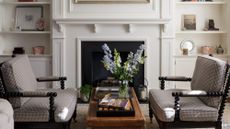 White walled living room with black gingham accent chairs and a wooden coffee table