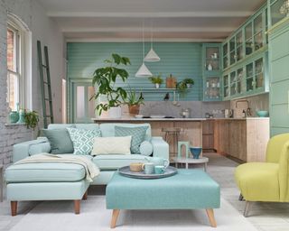 A pastel or mint green living room with kitchen in background