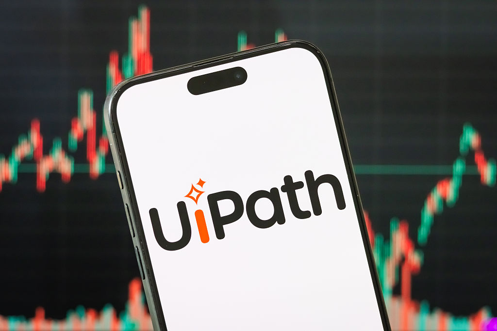 UiPath logo on a smartphone with a stock chart in the background