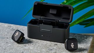 DJI Mic Mini case open with both mics on a stone surface around the case.