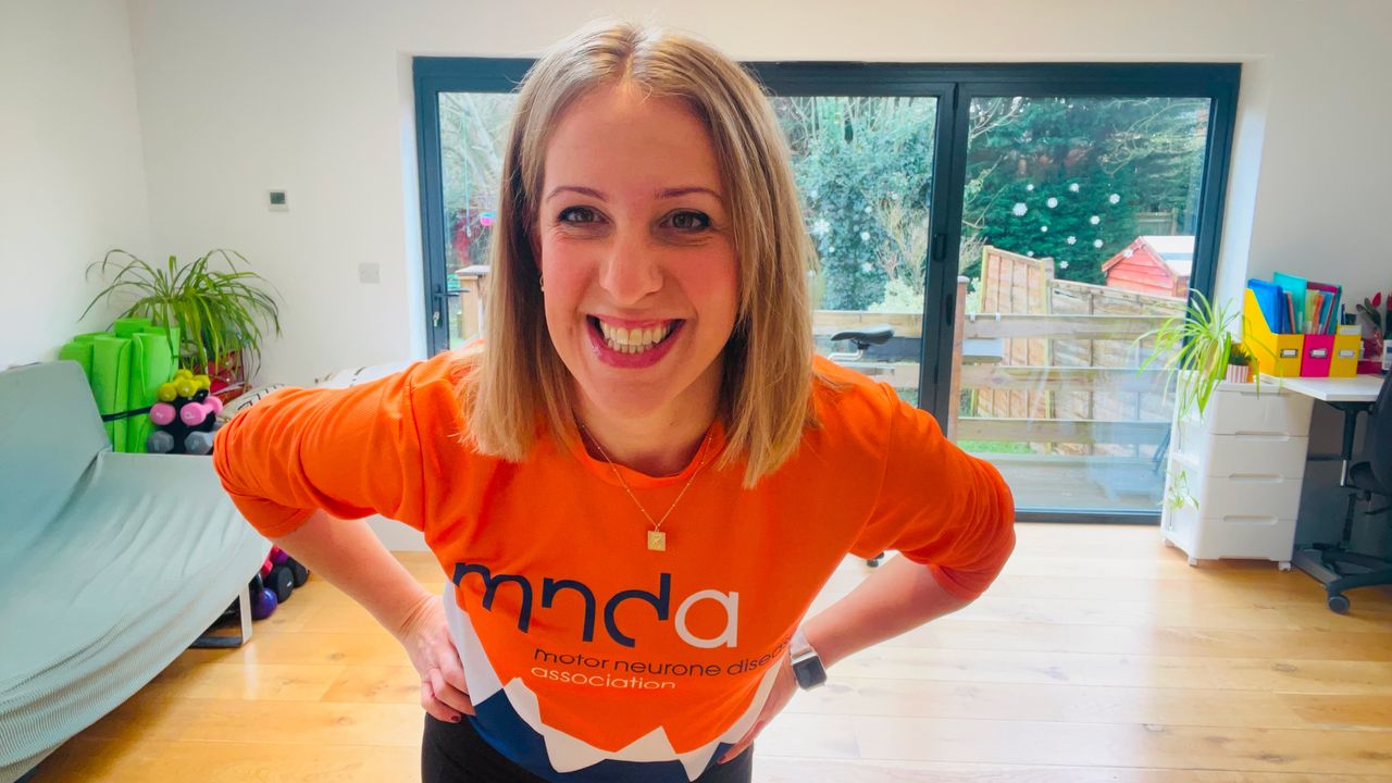 Woman wearing orange T-shirt leans towards camera smiling