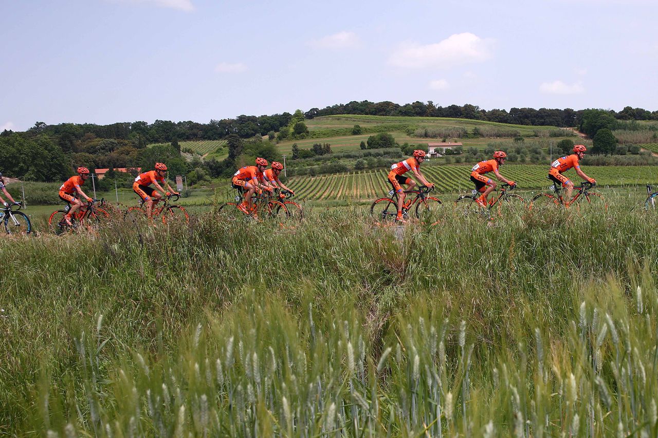 The landscape of Toscana dotted with the orange kits of CCC Sprandi