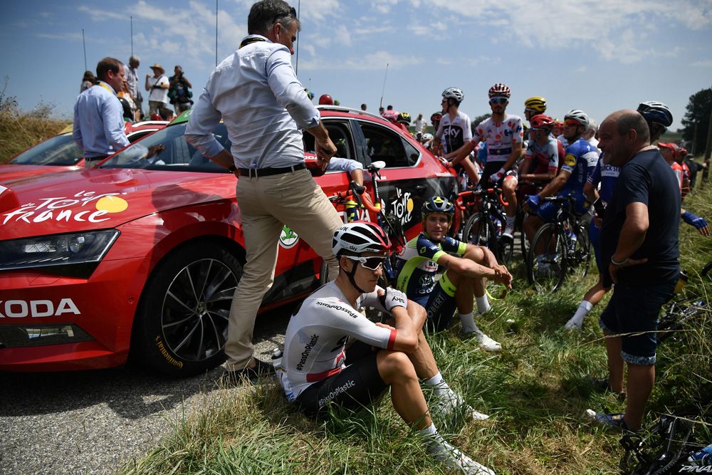 Riders sit near the Tour de France directors car after the protest