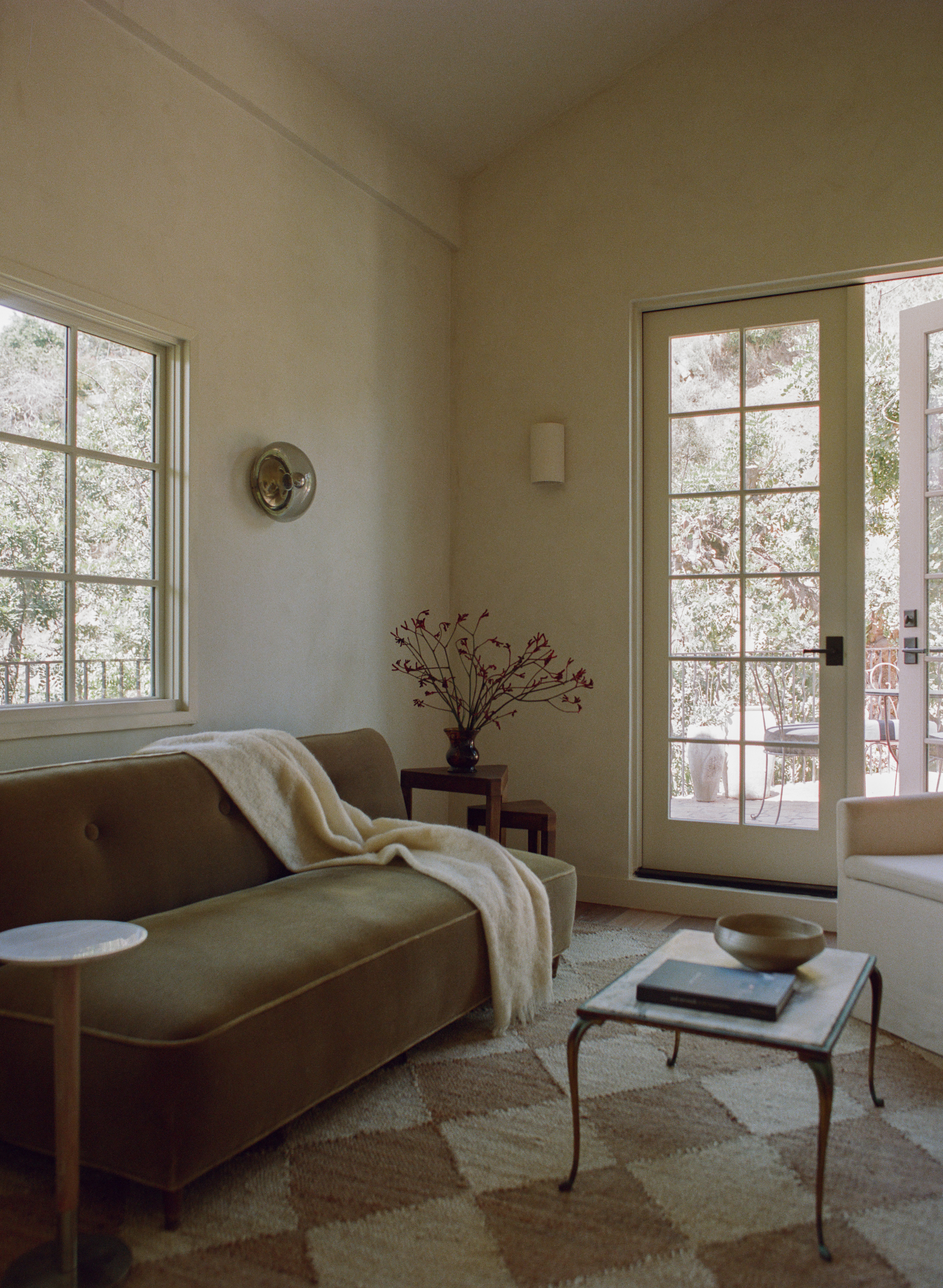 A calming living room with an olive green sofa and beige walls.