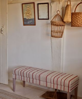 rustic entryway with upholstered bench and hanging vintage baskets and art