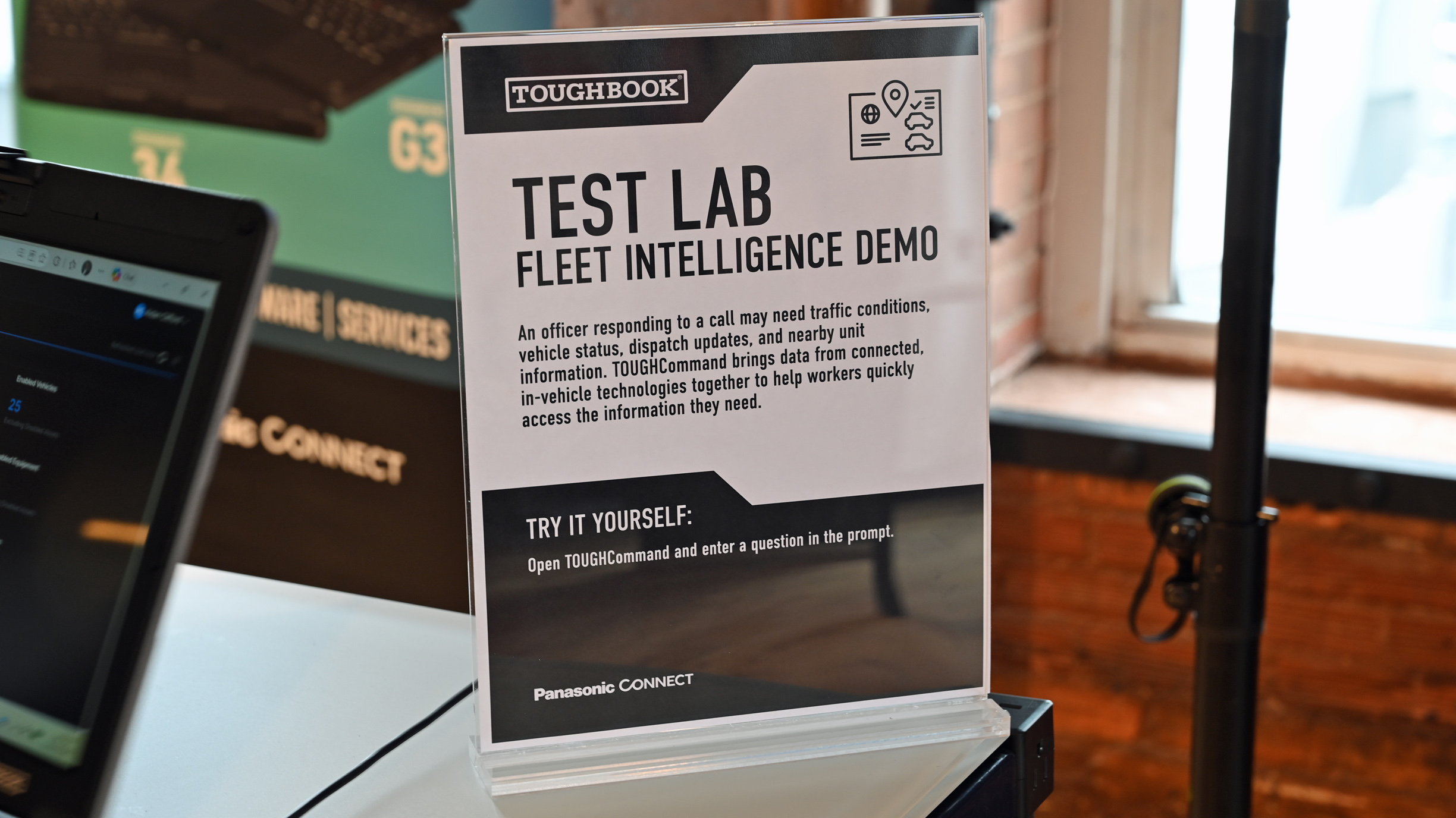 An informational display sign reading "TEST LAB FLEET INTELLIGENCE DEMO" standing beside a Panasonic TOUGHBOOK laptop.