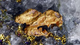 A large gold nugget sits embedded in quartz crystals.