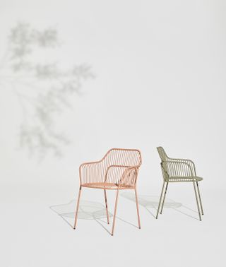 Two armchairs for dining outdoors by Benjamin Hubert for Allermuir in pink and green, with a hint of shadow in one corner