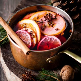 Pot on hob with mulled wine, orange slices, and cinnamon sticks