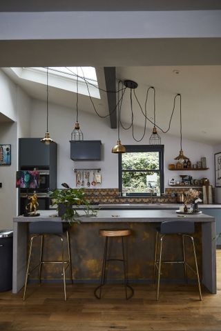 A kitchen with Edison bulbs hanging from the ceiling, on wires, and a concrete worktop