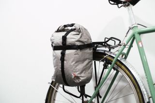 A small silver pannier mounted to a green bike against a white background