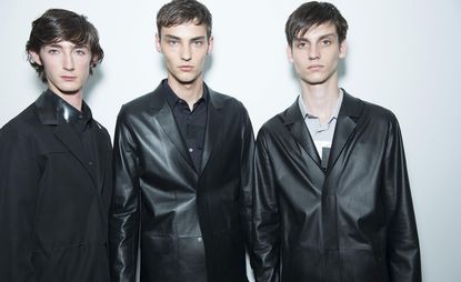Close up shot of 3 male models in dark clothing posing for the camera