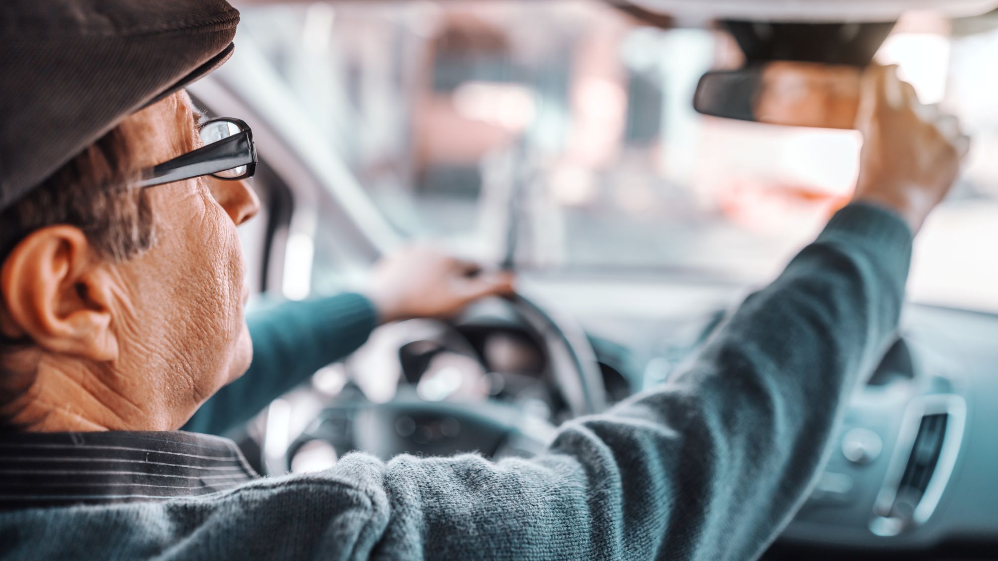 A man adjusting his rearview mirror 