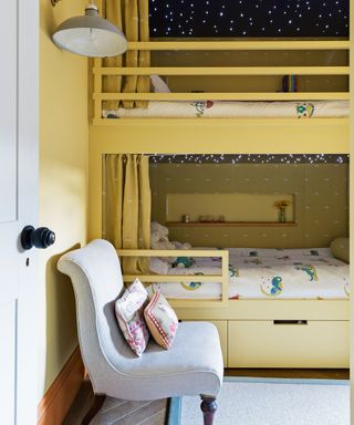 Kids' room paint ideas illustrated in a yellow bedroom with painted bunk beds and a pale gray chair.