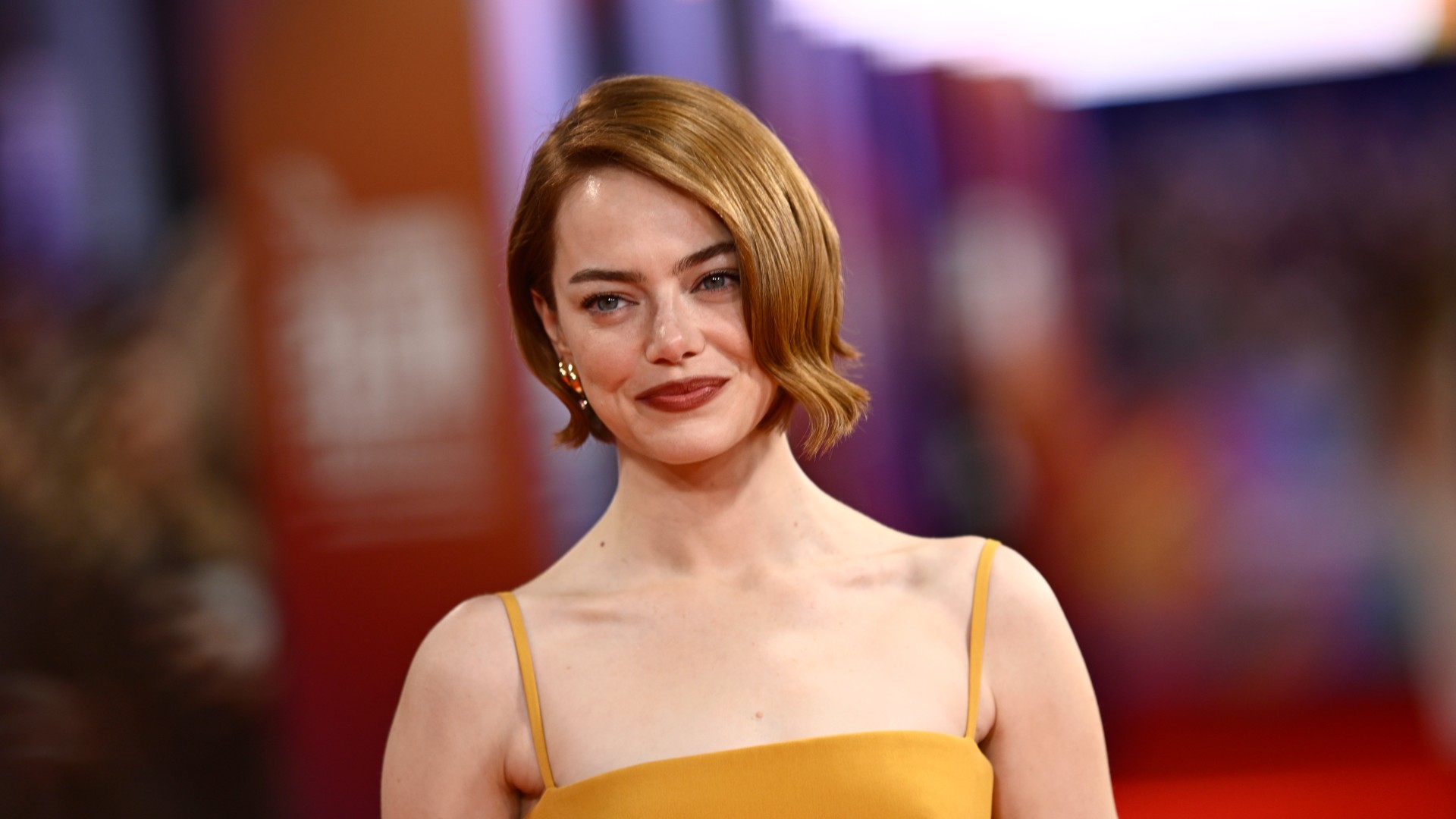 a white woman with short, red hair being photographed at a red carpet film premiere