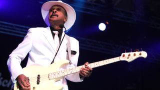 Larry Graham playing bass in a white suit