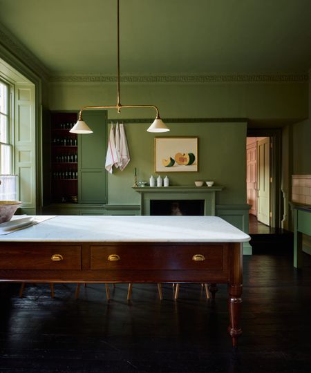 deVOL Heirloom kitchen featuring a freestanding Dairy Table with a marble worktop, painted green cabinetry, dark wood flooring and a traditional fireplace.