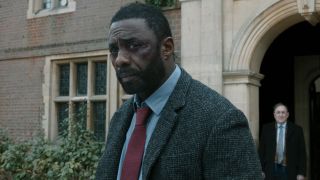 Idris Elba and Dermot Crowley standing outside, with faces of uncertainty, in Luther: The Fallen Sun. 