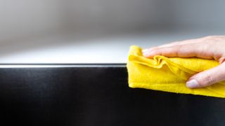 person using a microfiber cloth to clean a kitchen surface