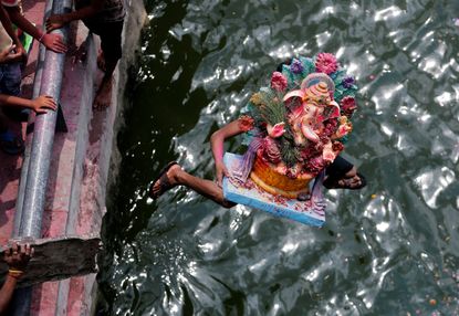 A devotee carrying an idol of the Hindu god Ganesh, the deity of prosperity, jumps into the Sabarmati river to immerse the idol on the last day of the ten-day-long Ganesh Chaturthi festival i