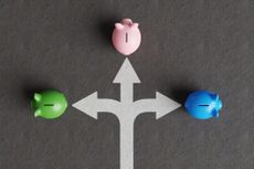 White divided road sign mark on asphalt with 3 different colored piggy banks (green, pink and blue) going to different directions. 