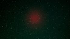 A faint red blob of light in the night sky