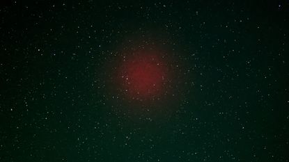 A faint red blob of light in the night sky